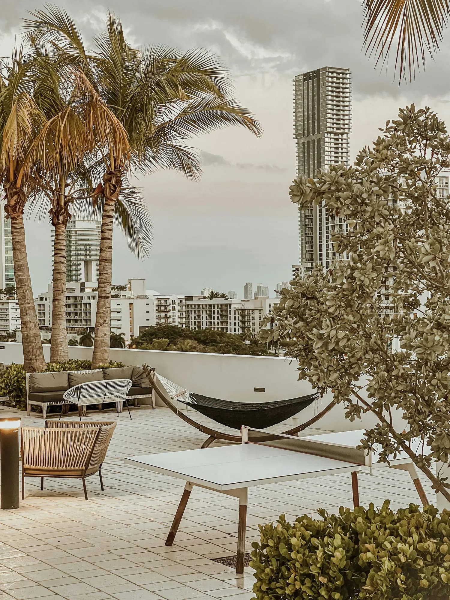 A rooftop terrace with a hammock and mid-rise buildings behind it