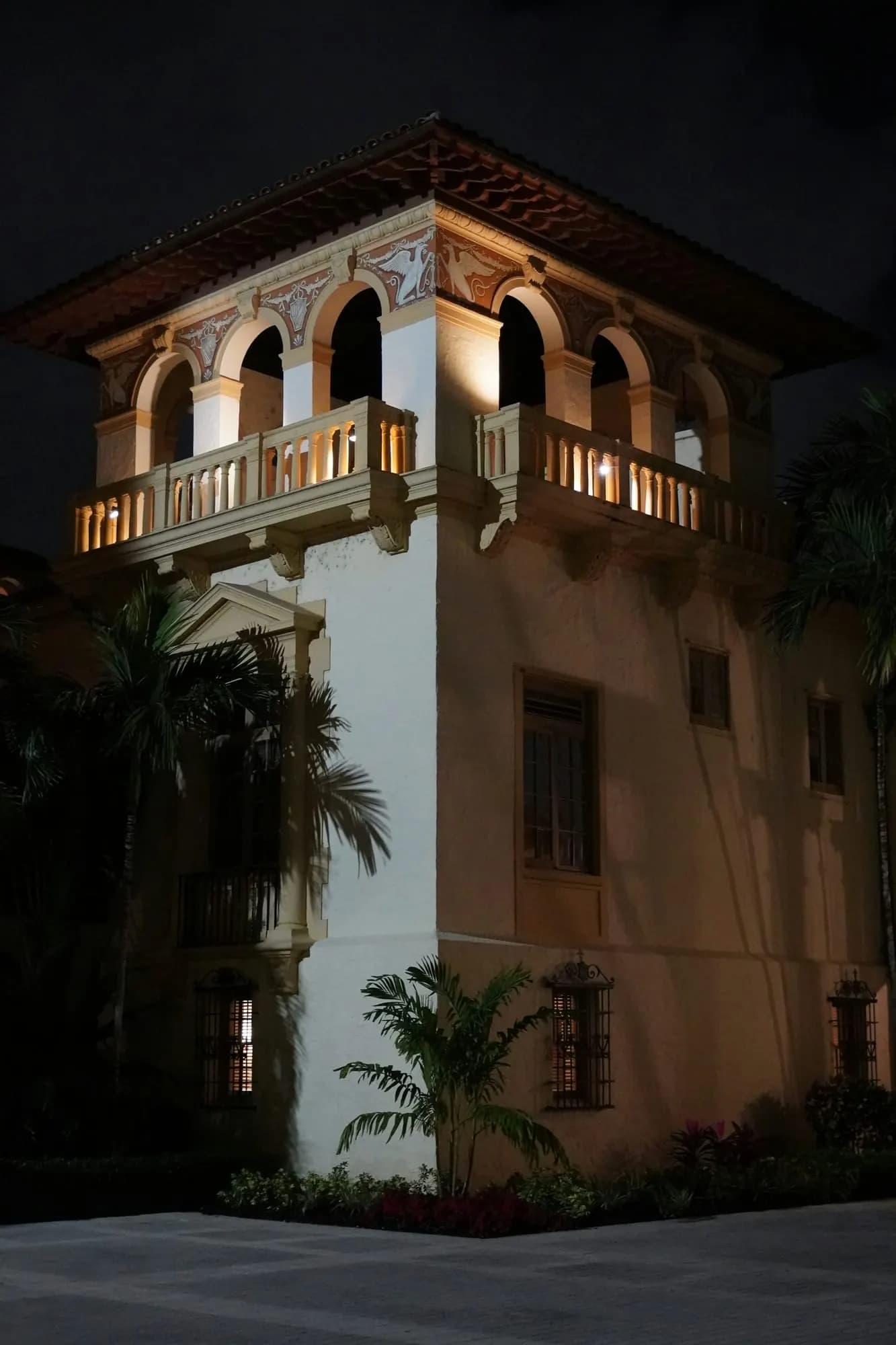 A Mediterranean Revival facade with arches and balconies, at night