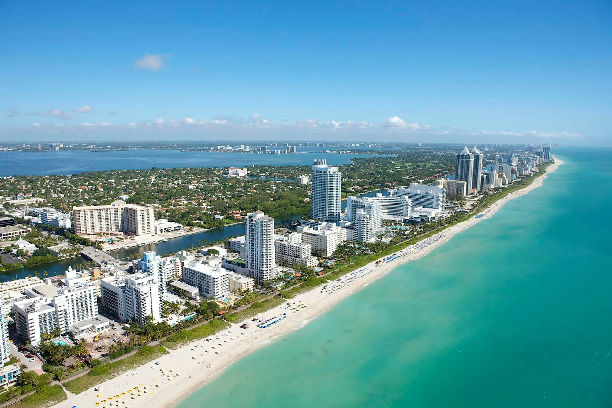 A shoreline, turquoise water and the built fabric running along the coast — from the air